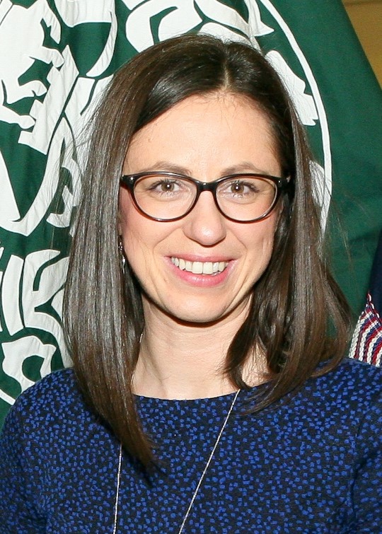 Portrait photo of Anja Neundorf, a Caucasian woman with dark, shoulder-long hair and black-rimmed glasses wearing a dark blue sweater.